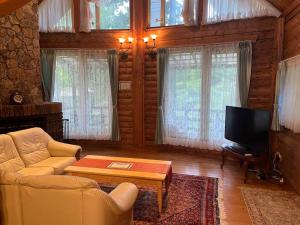 a living room with a couch and a tv at Kurokawa Marigold in Minamioguni