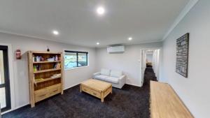 sala de estar con silla y estante para libros en 5 Bedroom, Solar on Snowmass Ohakune, Yellow Door en Ohakune