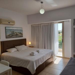 1 dormitorio con cama y ventana grande en King's Holiday Apartments, en Pafos