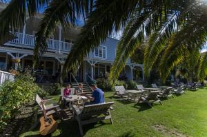 a man and woman sitting at tables under a palm tree at Ōtoromiro Hotel in Governors Bay