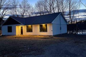 a small white house with a black roof at Riverside Getaway with HotTub 3br 2 bth in Brewer