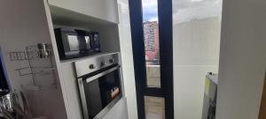 波哥大的住宿－Wohnung Queens Deluxe，厨房配有微波炉,电视位于烤箱顶部