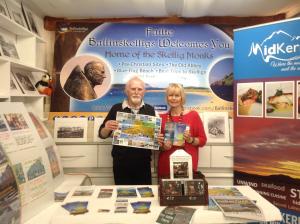 un hombre y una mujer parados frente a una mesa con libros en The Old School House B&B en Ballinskelligs