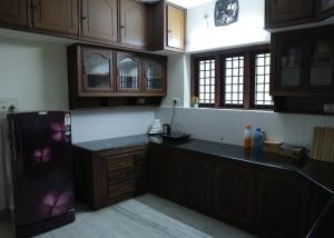 a kitchen with wooden cabinets and a black counter top at Malpans Mansion Villa in Nedumbassery