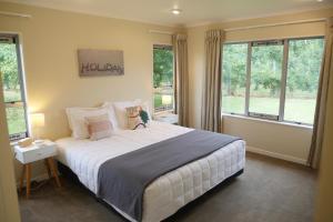 a bedroom with a large white bed with windows at Lodge On St Georges in Havelock North