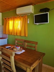a wooden table with two chairs and a television on a green wall at El refugio Anillaco in Anillaco