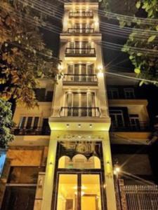 un grand bâtiment blanc avec une tour d'horloge la nuit dans l'établissement Sophia Hotel, à Hai Phong