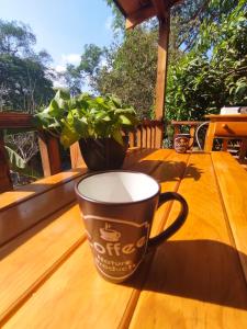 una taza de café sobre una mesa de madera en un porche en La cabaña de Aurora en Comala