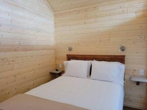 ein Schlafzimmer mit einem weißen Bett in einem Holzzimmer in der Unterkunft 081 Tiny Home nr Grand Canyon South Rim Sleeps 8 in Valle