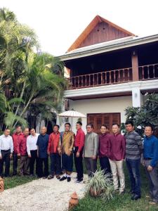 a group of men standing in front of a house at wisdom mystery Hotel in Luang Prabang