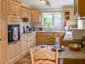 a kitchen with wooden cabinets and a table with a bottle at Meadow View in Hockering