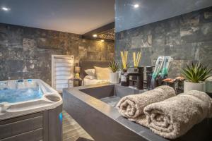 a bathroom with a tub and a sink with towels at L'Eden Love - Jacuzzi / Sauna in Grenoble