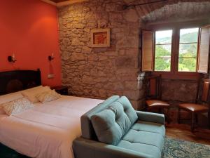 a bedroom with a bed and a blue couch at Agroturismo La Casona de Belmonte in Oviñana