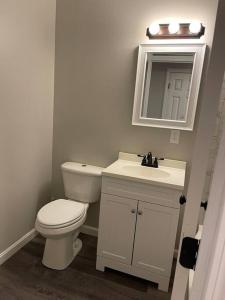 a bathroom with a toilet and a sink and a mirror at Spacious Home near Airport in Bangor