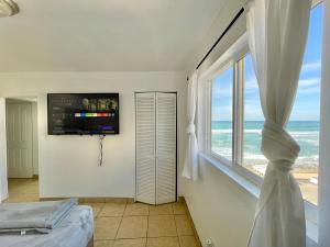 a bedroom with a large window with a view of the ocean at Beachfront, sun, sand & fun - Cozy 1 Bdr Apt in Tijuana