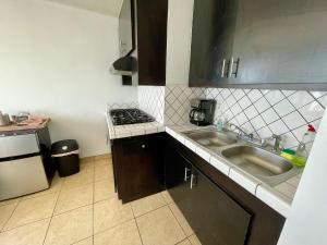 a small kitchen with a sink and a stove at Beachfront, sun, sand & fun - Cozy 1 Bdr Apt in Tijuana