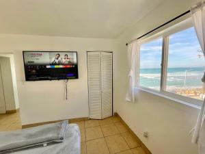 a living room with a tv and a large window at Beachfront, sun, sand & fun - Cozy 1 Bdr Apt in Tijuana +14 photos