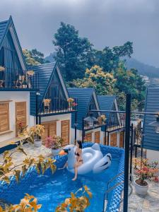 a girl in a bathing suit jumping on an inflatable at CuDen Homestay Venuestay in Vĩnh Phúc