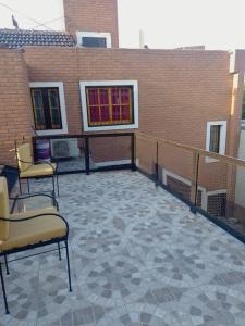 un patio con 3 sillas y un edificio de ladrillo en Hermoso departamento super tranquilo y espaciado en Córdoba