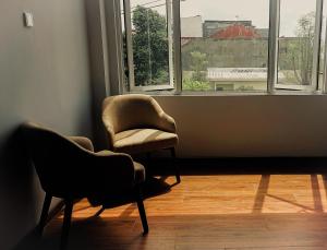2 Stühle in einem Zimmer mit Fenster in der Unterkunft AYMAN SYARIAH HOTEL in Surabaya