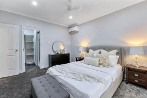 a white bedroom with a large bed and a mirror at The OC Home: Centrally Located, Home Away Home in Nightcliff