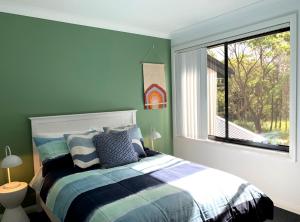a bedroom with a bed and a large window at The Place - Culburra Beach in Culburra Beach
