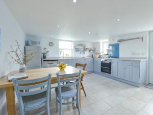 a kitchen with a wooden table and blue cabinets at 2 Trerise Cottage in Helford