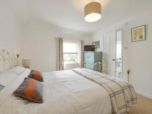 a bedroom with a large white bed and a window at 2 Trerise Cottage in Helford