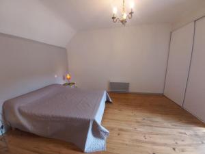 een slaapkamer met een bed en een houten vloer bij Maison avec jardin in Adé