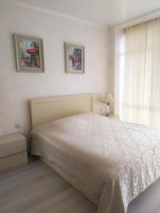 ein Schlafzimmer mit einem weißen Bett und einem Fenster in der Unterkunft Family apartament in Batumi
