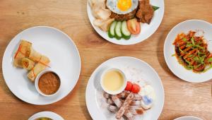 four white plates of food on a wooden table at Palm Springs Bali Dive Resort in Tulamben