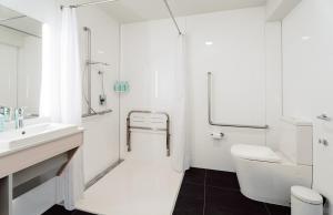 uma casa de banho branca com um lavatório e um WC em CitySide Hotel Tauranga em Tauranga