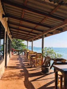 un portico in legno con tavoli e sedie e l'oceano di Rock sand Resort a Trat