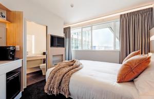 pokój hotelowy z łóżkiem i dużym oknem w obiekcie CitySide Hotel Tauranga w mieście Tauranga