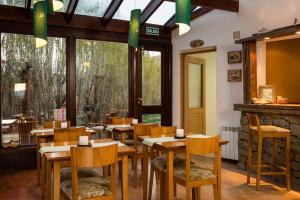 a restaurant with wooden tables and chairs and windows at Hosteria Roblesur in El Calafate