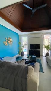 Kluai Mai Luxury Pool Villa, Panorama Resort في هوا هين: غرفة معيشة مع أريكة والجدار الأزرق
