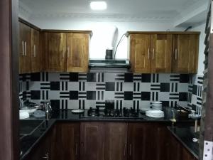 a kitchen with wooden cabinets and black and white tiles at CEYLON VILLA NILAVELI in Trincomalee