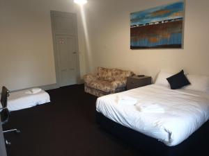 ein Hotelzimmer mit 2 Betten und einem Sofa in der Unterkunft Leura Hotel in Camperdown