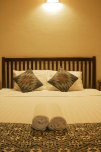 a bed with two pillows and two towels on it at laolulodge in Luang Prabang