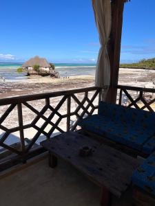 a bench on a beach with an umbrella and the ocean at The View of Zanzibar in Michamvi