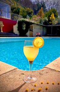 a glass of orange juice sitting next to a swimming pool at Villa Belle Vue in Saint Paul de Vence