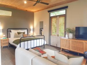ein Schlafzimmer mit einem Bett, einem Sofa und einem TV in der Unterkunft Clonmara Country House and Cottages in Port Fairy