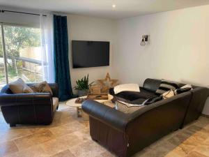 un salon avec deux canapés et une télévision à écran plat dans l'établissement Villa les Romarins, à Saint-Didier