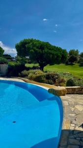 einem blauen Pool vor einem Golfplatz in der Unterkunft VILLA DANS CADRE D'EXCEPTION - GOLF, PISCINE ET TENNIS PRIVE in Saint-Cyr-sur-Mer