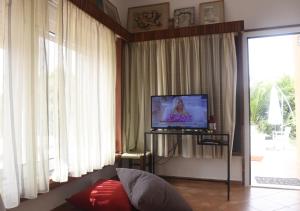 a living room with a flat screen tv and curtains at Τhe banana tree beach house in Marathon