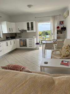 una cucina e un soggiorno con armadi bianchi e tavolo di Dina Apartment a Skala di Cefalonia