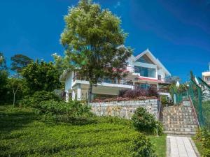 a house with a retaining wall and a tree at amã Stays & Trails - Werifesteria, Coonoor in Coonoor