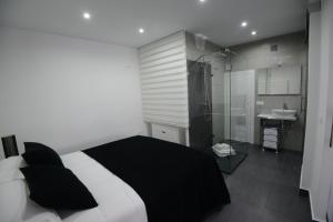 1 dormitorio con 1 cama en blanco y negro y baño en Apartamentos Torrecilla, en Jarandilla de la Vera