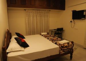 a bedroom with a bed and a table and a television at Malpans Mansion in Nedumbassery
