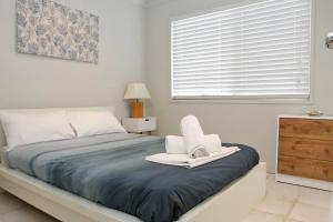 een slaapkamer met een bed met een blauwe deken en een raam bij KIAMA AMITY POINT in Amity Point